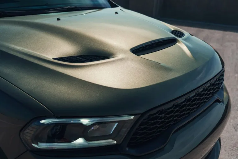 Image 14: Close-up of a car hood featuring a textured surface and stylish air vent.