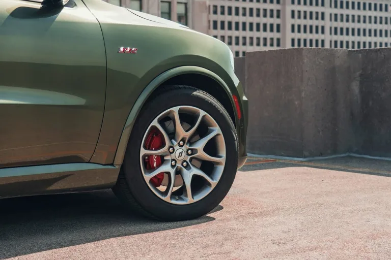 Image 15: Close-up of a green SUV with a stylish wheel and brake caliper on a rooftop parking area.