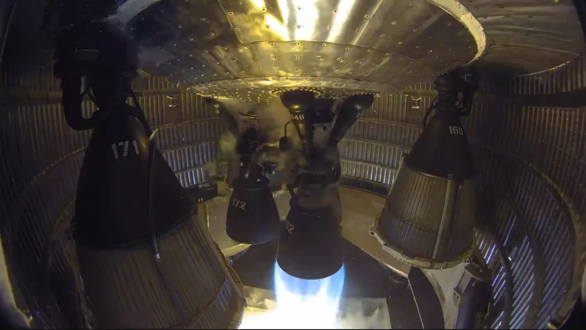 Image 24: One of six rocket engines in an enclosed aft rocket section fires into a test stand.