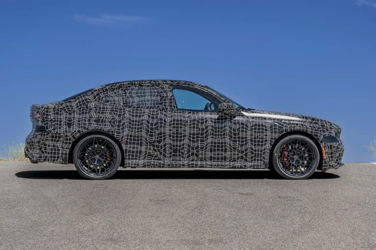A car covered in camouflage vinyl wrap on a winding road with a clear blue sky. A car covered in camouflage vinyl wrap on a winding road with a clear blue sky.