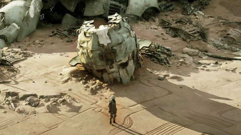 A weathered robot head lies in the sand.