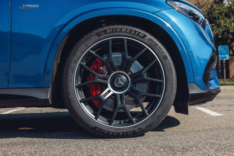 Close-up of a blue car's wheel, featuring black alloy rims and red brake calipers. Close-up of a blue car's wheel, featuring black alloy rims and red brake calipers.