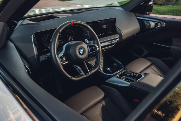 Interior view of a BMW car showcasing the steering wheel and dashboard display. Interior view of a BMW car showcasing the steering wheel and dashboard display.