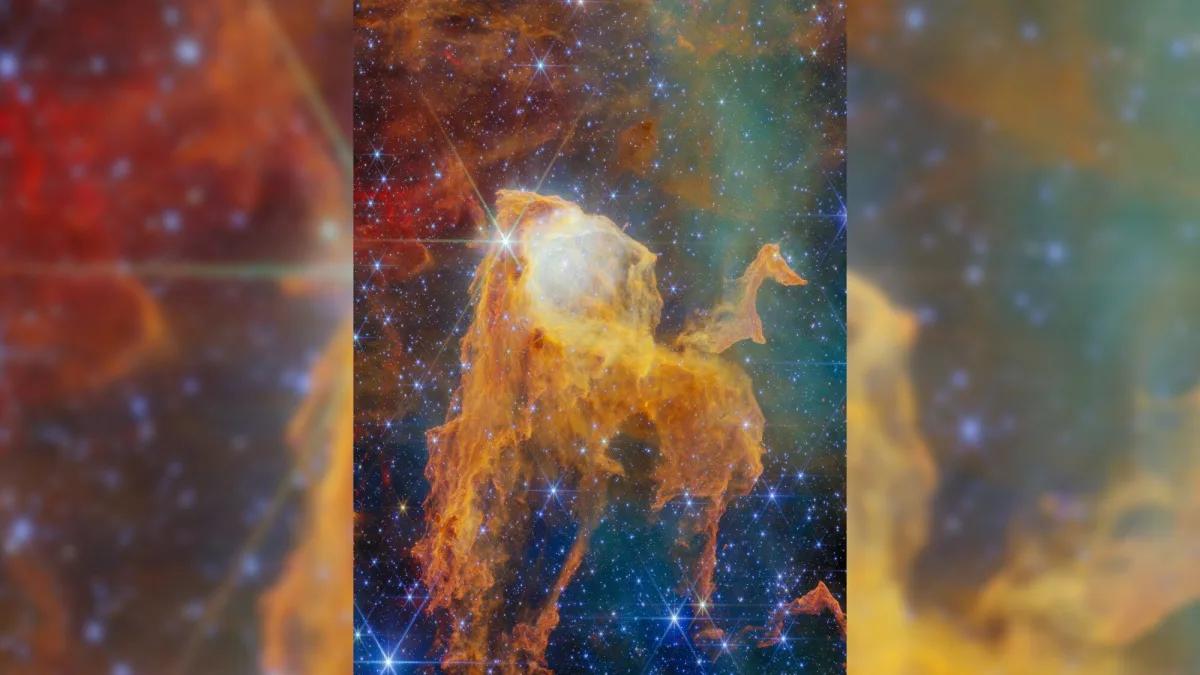 Image 23: A JWST nebula image shows a large central yellow gas and dust nebula surrounded by twinkling stars and gas and dust in red, orange, blue and green.